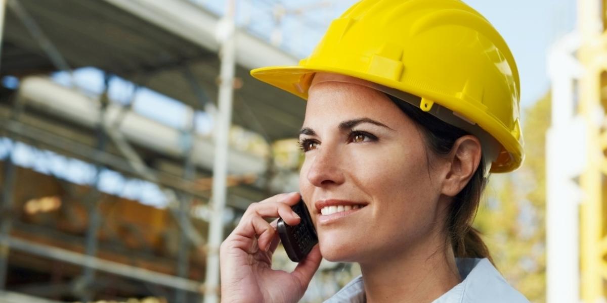 En kvinna på en byggarbetsplats med en GroupTalk telefon i ett PTT gruppsamtal