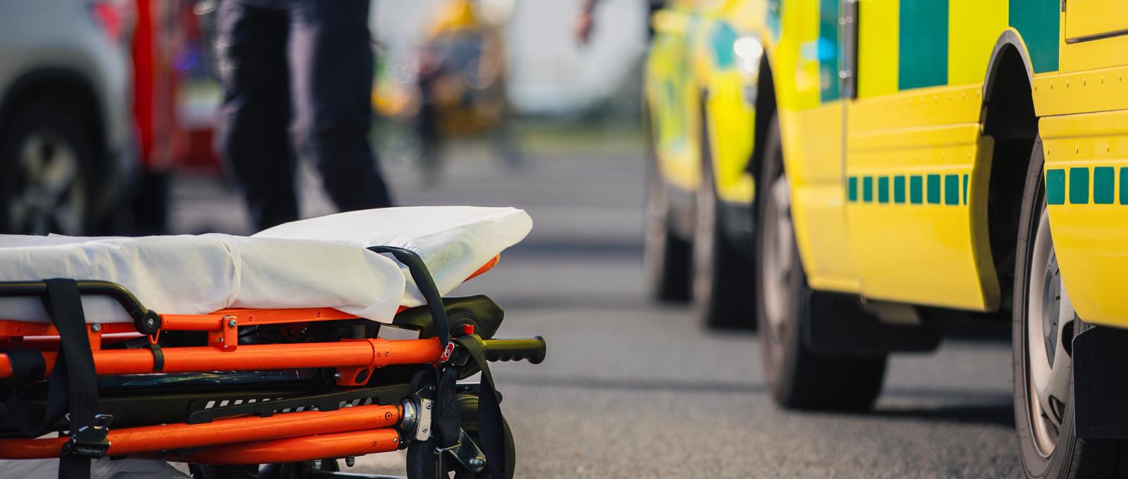 Ambulans med bår som ligger på marken