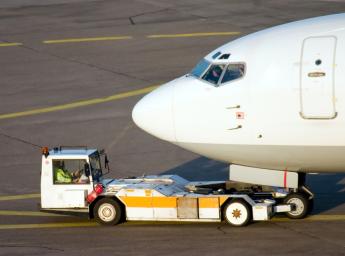 Flygplatspersonal skjuter in flygplan i hangar för förvaring.
