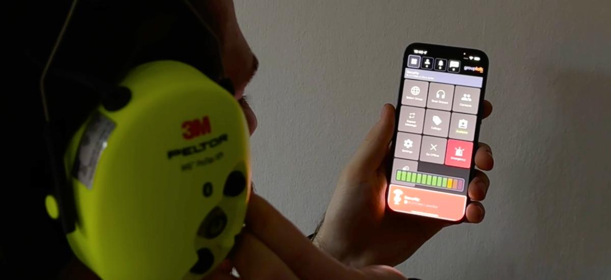 Man använder GroupTalks PTT-app på iPhone med 3M Peltor-headset.