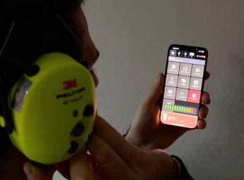 Man använder GroupTalks PTT-app på iPhone med 3M Peltor-headset.
