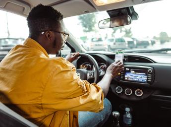 Taxichaufför använder push to talk-app på smartphone för internkommunikation.