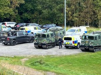 Polis- och militärfordon står parkerade tillsammans på ett stort fält.