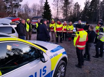 En stor grupp poliser och volontärer står i en cirkel.