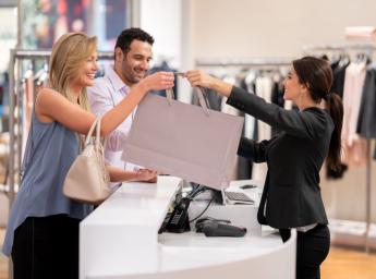 Butiksanställd överlämnar en kasse till kund i kassan.