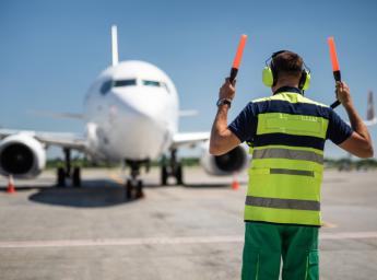 Markpersonal hjälper en pilot att parkera flygplanet vid gaten.