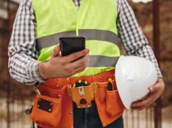 Arbetare på byggarbetsplats kommunicerar med teamet via smartphone.