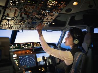 Kvinnlig pilot hanterar reglage i cockpit.