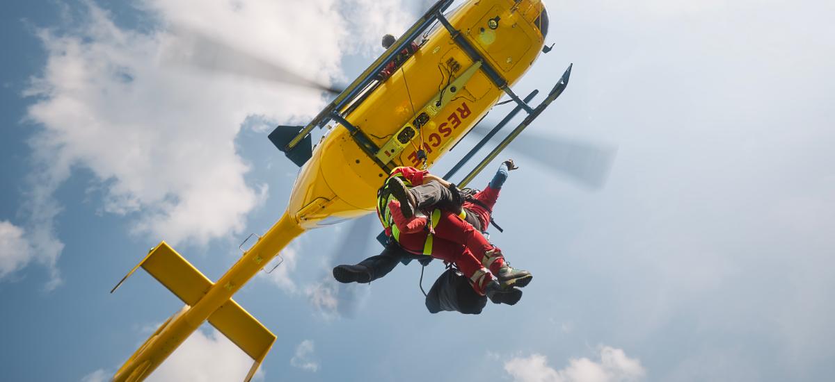 Räddningsarbetare som firar sig ner från helikopter med rep.