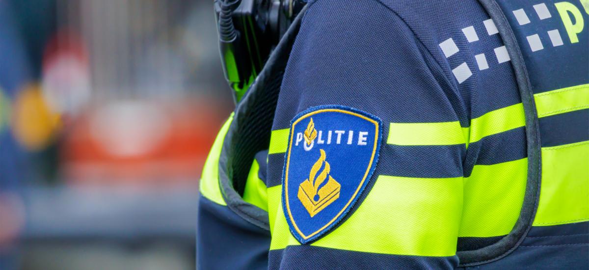 Närbild på holländsk polisuniform med officiell bricka.