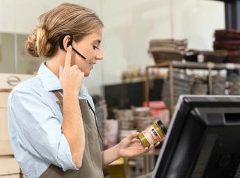 Arbetare använder push to talk för teamkommunikation i butik.