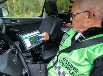 Volontär för Missing People sitter i en bil och övervakar sökteamet via en iPad.