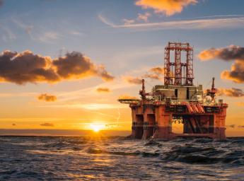 Oljerigg offshore i solnedgång till havs