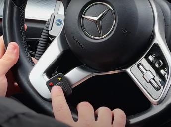 Taxichaufför trycker på en push to talk-knapp i bilen.