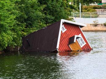 Översvämmat hus omgivet av vatten.