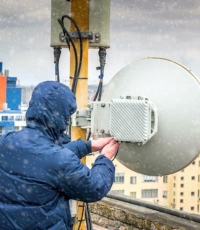 En person står på ett tak av en byggnad och ställer in ett gamalt komradio system.