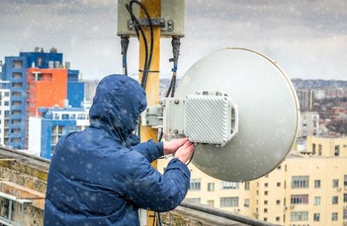 En person står på ett tak av en byggnad och ställer in ett gamalt komradio system.